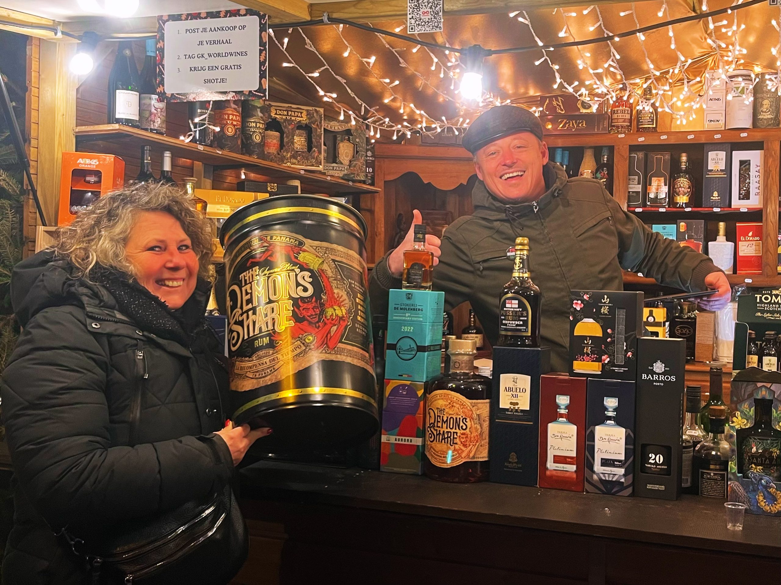 Korneel achter de Vloeibār-kraam met een brede selectie rum en whisky, samen met een tevreden klant